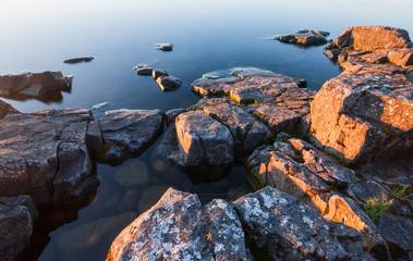 Rocks of stony coast in calm water of lake
