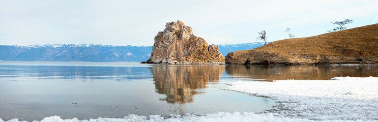 Fototapeta na wymiar Lake Baikal on a spring morning. Panorama of the coast of Olkhon Island with melting ice near the Shamanka Rock