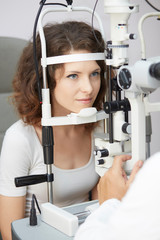 pretty young woman having her eyes examined by an eye doctor
