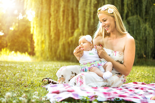 Mother with baby daughter enjoying time together in the park at sunset.