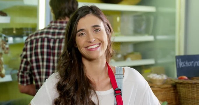 Smiling female staff standing with hand on hip in organic section