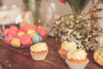 Bright macaroons and cupcakes on a table