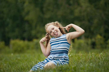 Fototapeta premium Pretty blonde smiling child wearing summer dress is playing in park