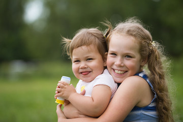 A portrait of two sisters on green grass, park outdoor