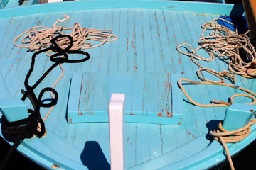 blau weißes Fischerboot aus Holz am Meer schwimmend, Blick in ein kleines Holzboot, Erholung im Süden am Wasser