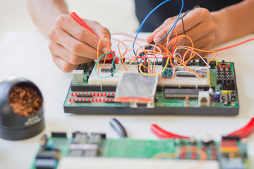 Multimeter examining a circuit board.Young energetic male tech or engineer repairs electronic...