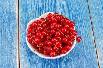 Red currants in ceramic bowl on wood backgroun