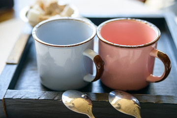 Tea set with two metal cups and spoons on tray
