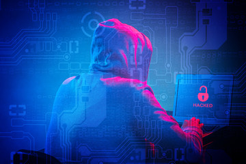 Hooded computer hacker stealing information with laptop