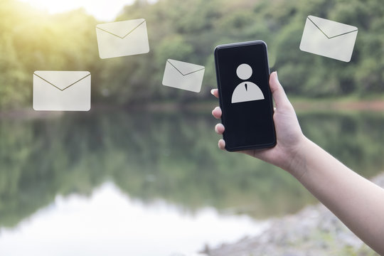 Hand hold telephone receiving e-mail on nature background