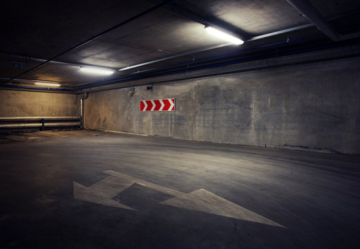 Urban underground background. Concrete wall under the lamp light in the dark with white arrow on the ground.