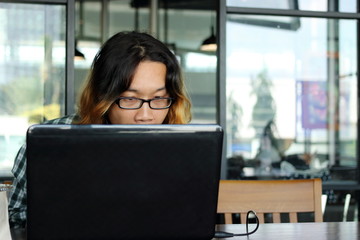 Close up young Asian worker looking his laptop in office against copy space background.