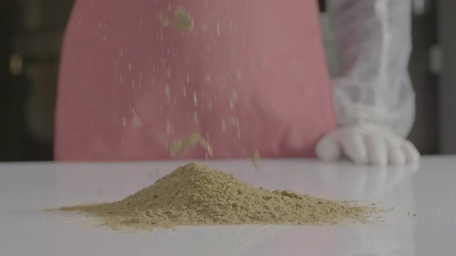 ground cumin power falling into a white kitchen table. super slow