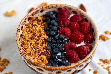 Bowl of homemade granola with yogurt and fresh berries on white background. Close up view. Collection