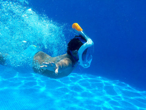 El ni&ntilde;o esta buceando en la piscina con easy breath mask