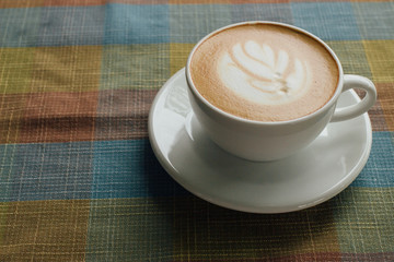 Coffee cup latte art with tree shape foam top view on wooden table background in coffee shop
