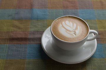Coffee cup latte art with tree shape foam top view on wooden table background in coffee shop