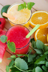 Smoothies from orange and tangerine and smoothie from watermelon with mint on wooden background