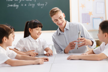 Male teacher helping students study in classroom