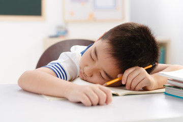Tired school boy having rest in classroom
