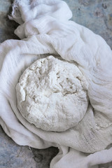Fresh cooking homemade cottage cheese in gauze textile over gray metal background. Top view. Rustic style, day light