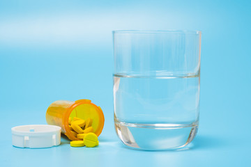 Pills and medication and a glass with water on a blue  background