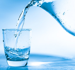 Drinking water is poured into a glass from a jug