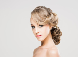 Portrait of gorgeous blond with a beautiful hair style on a grey background.