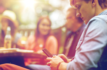 man with smartphone and friends at summer party