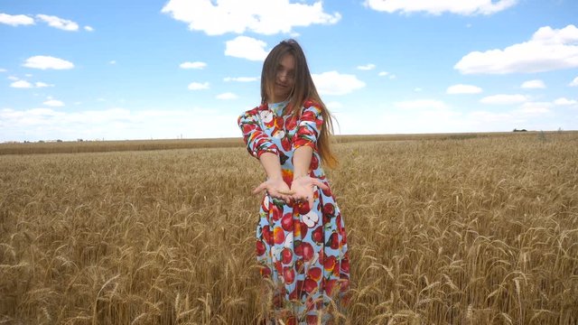 girl stands in the field dress and shows in the palms, wheat