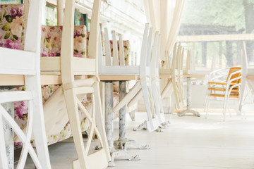 White chairs on tables upside down on street cafe summer terrace.