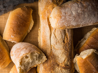 Freshly baked bread loaves on burlap dark wooden background. Texture closeup italian bakery products