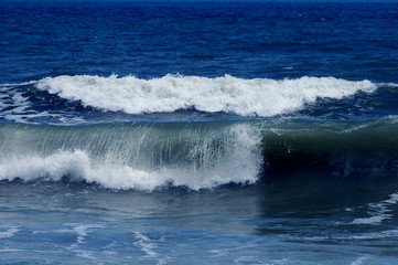 Ocean waves curling and crashing into the shallow water of the beach 