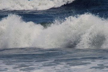 Ocean waves curling and crashing into the shallow water of the beach 