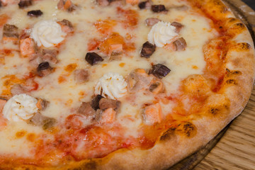 Hot piece of pizza with melted cheese on a rustic wooden table