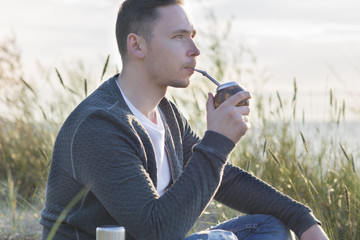 Young man drinking yerba mate on the Baltic sea coast