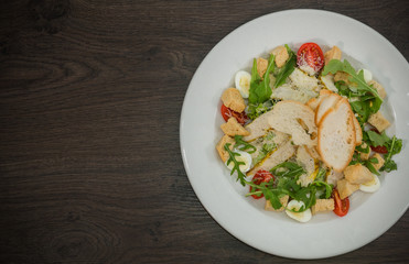 Fototapeta na wymiar Caesar salad in a white plate on a wooden background