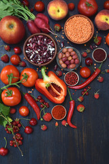 composition of red vegetarian products: fruit, vegetable and bean on wooden background. Apple, tomato, currant, radish, pepper, raspberries, cherry, lentils, olive. Healthy food. Copy space
