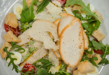 Caesar salad in a white plate on a wooden background