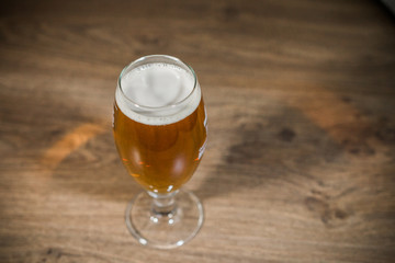 A glass of beer with foam on a wooden background