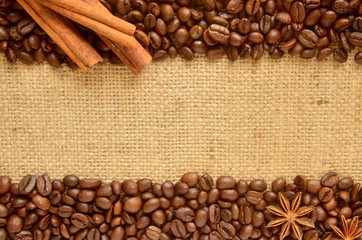 Whole roasted coffee beans at top and bottom of sackcloth with cinnamon bark and stars anise