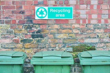 recycle trash can dustbins outside against brick wall