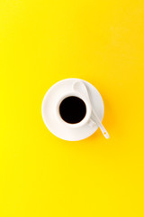 Coffee espresso in small white ceramic cup on yellow vibrant background. Minimalism Food Morning Energy Concept.