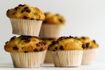 Many tasty homemade vanilla muffins with chocolate chunks on bright white background.