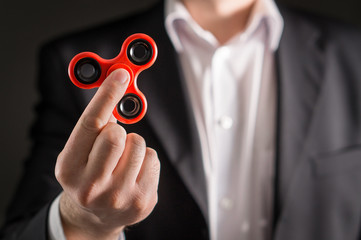 Business man with a fidget spinner. Businessman in a suit holding trendy kids anxiety relief toy in hand.
