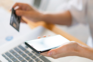 Fototapeta premium Hands holding a credit card using laptop computer and mobile phone for online shopping
