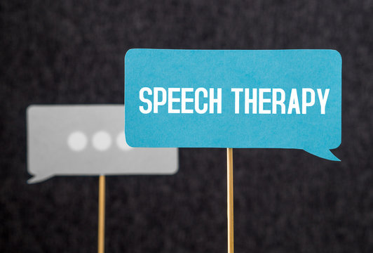Speech therapy text on cardboard speech balloon or bubble on wooden stick. Stuttering, lisp and learning to talk concept.