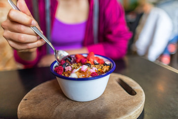 Acai bowl woman eating morning breakfast at cafe. Closeup of fruit smoothie healthy diet for weight loss with berries and oatmeal. Organic raw vegan healthy food.