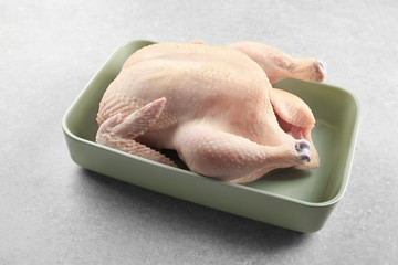 Whole raw turkey in casserole on grey background