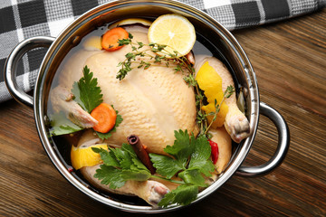 Cooking pot with turkey soaked in flavored brine on wooden table